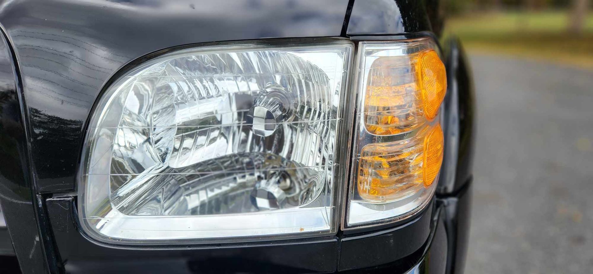 A close up of a car headlight on a road.