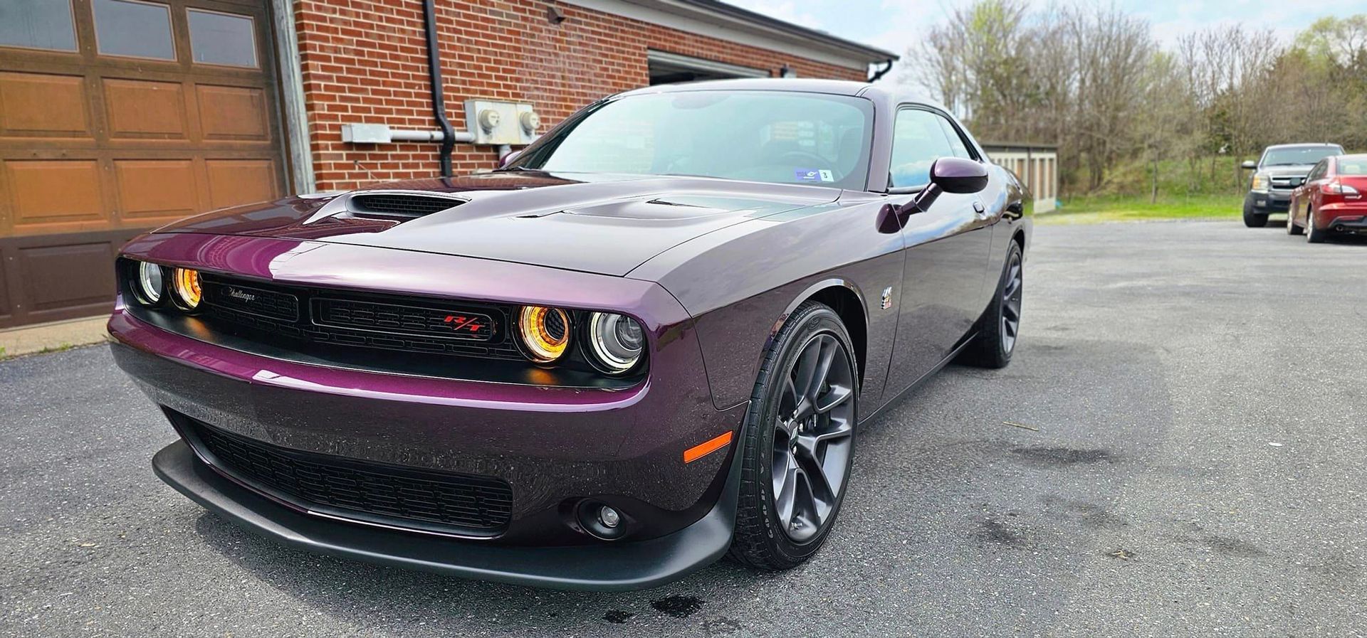 A purple dodge challenger is parked in front of a garage door.