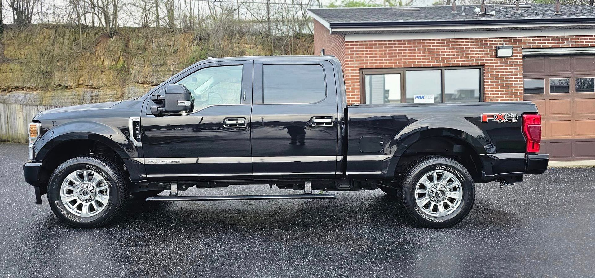 A black pickup truck is parked in front of a brick building.