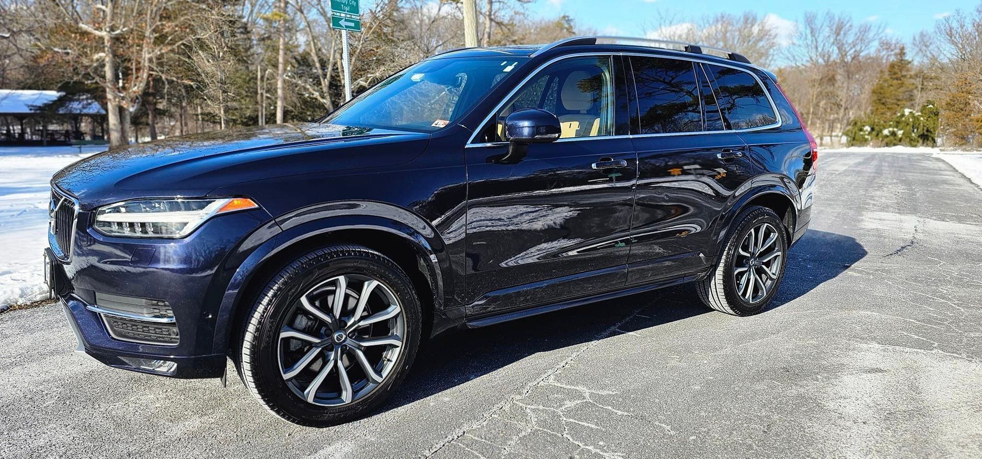 A black volvo xc90 is parked in a parking lot.