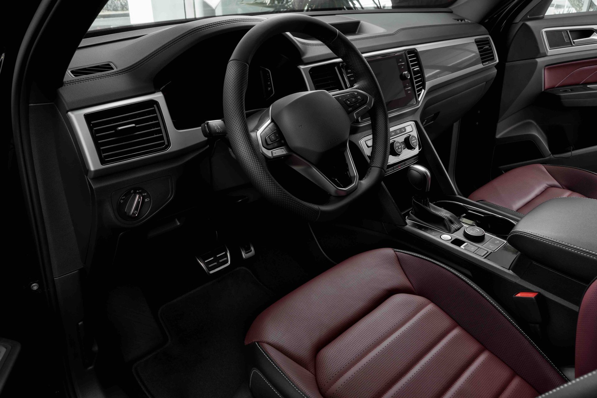 The interior of a black car with red leather seats and a steering wheel.