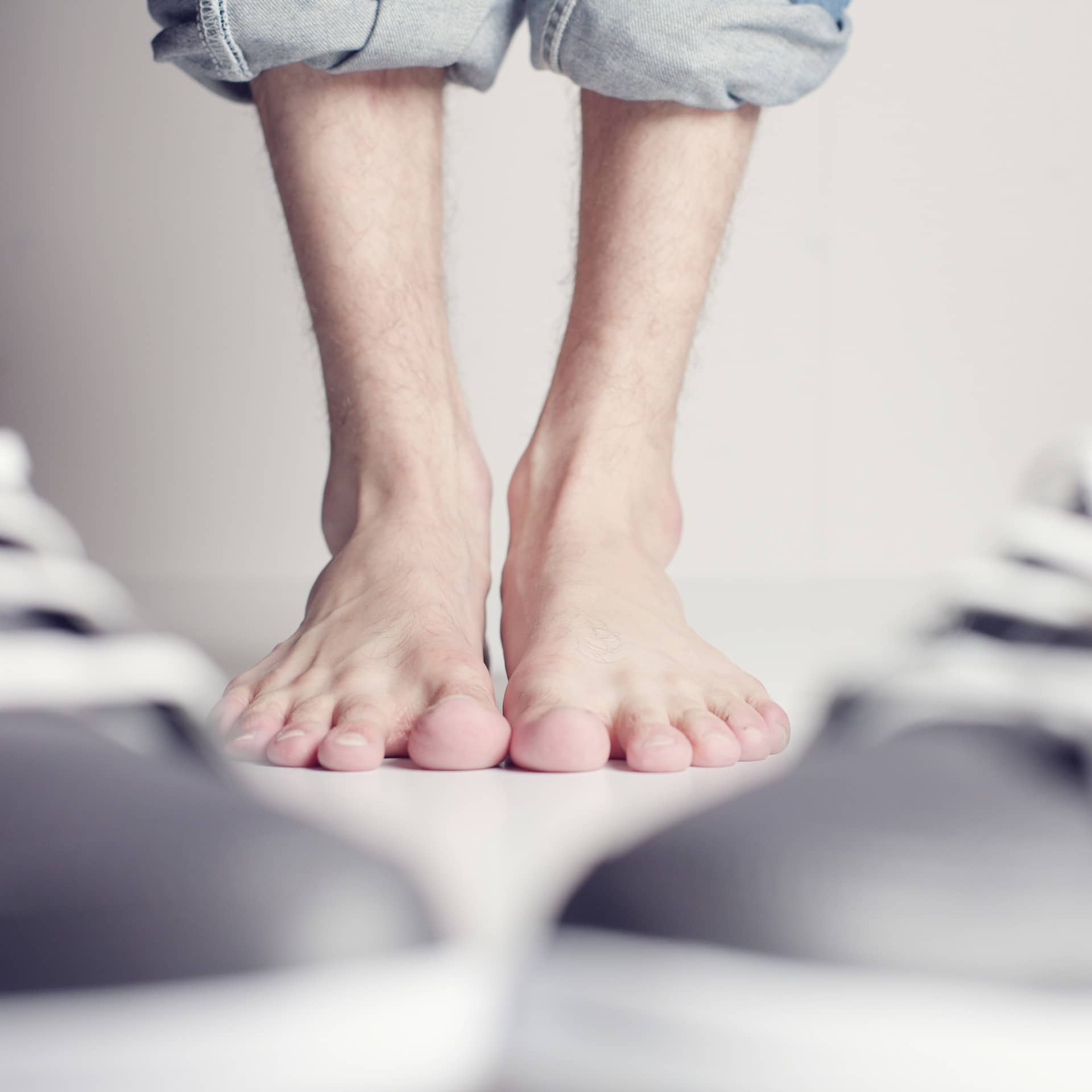 A person 's bare feet are standing next to a pair of shoes