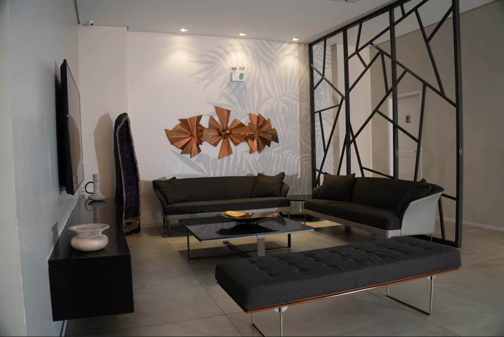 Sala de estar moderna com dois sofás, TV, decoração e divisória geométrica.