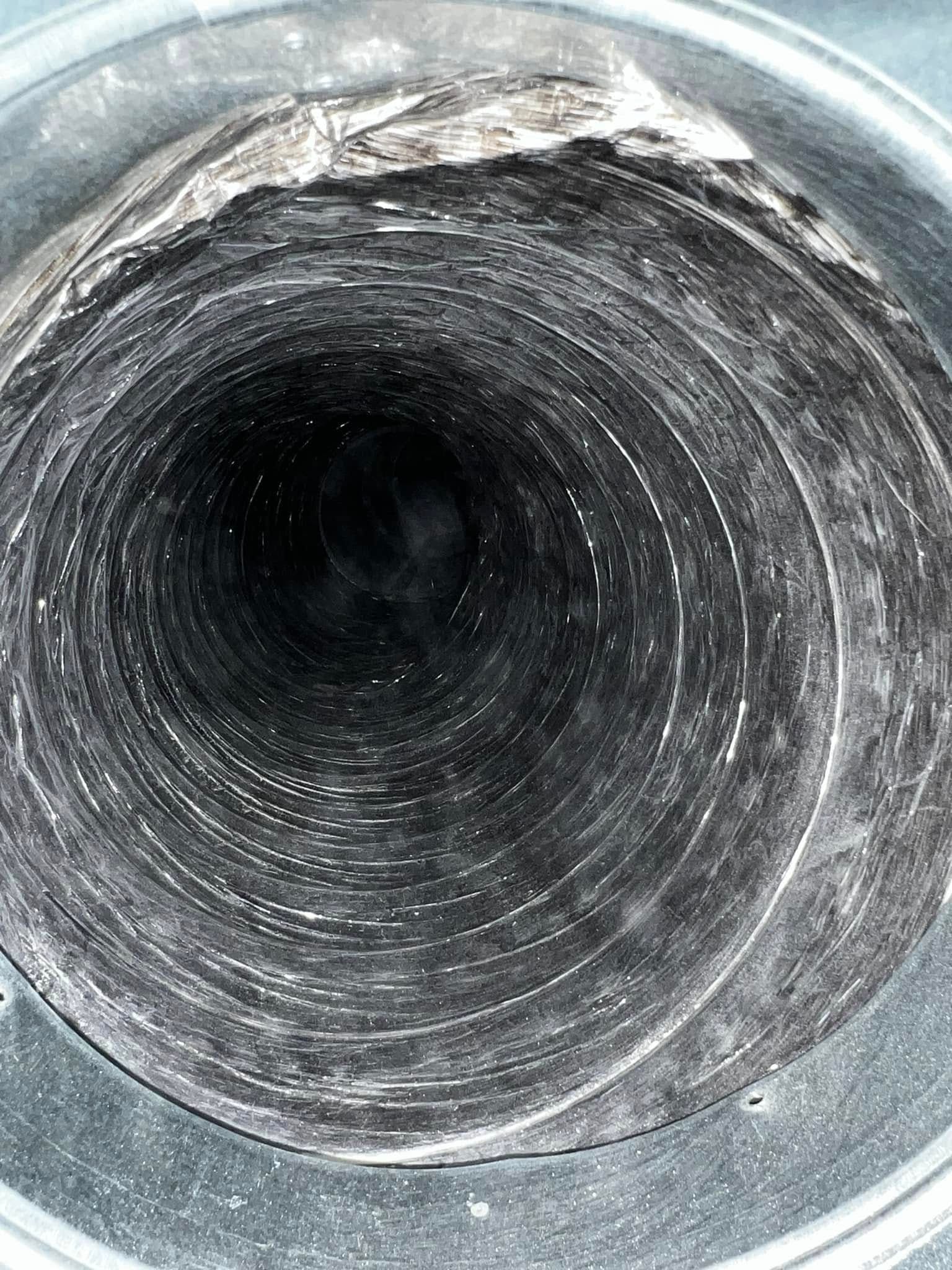 Close-up of a scratched silver metal tube opening with a dark center
