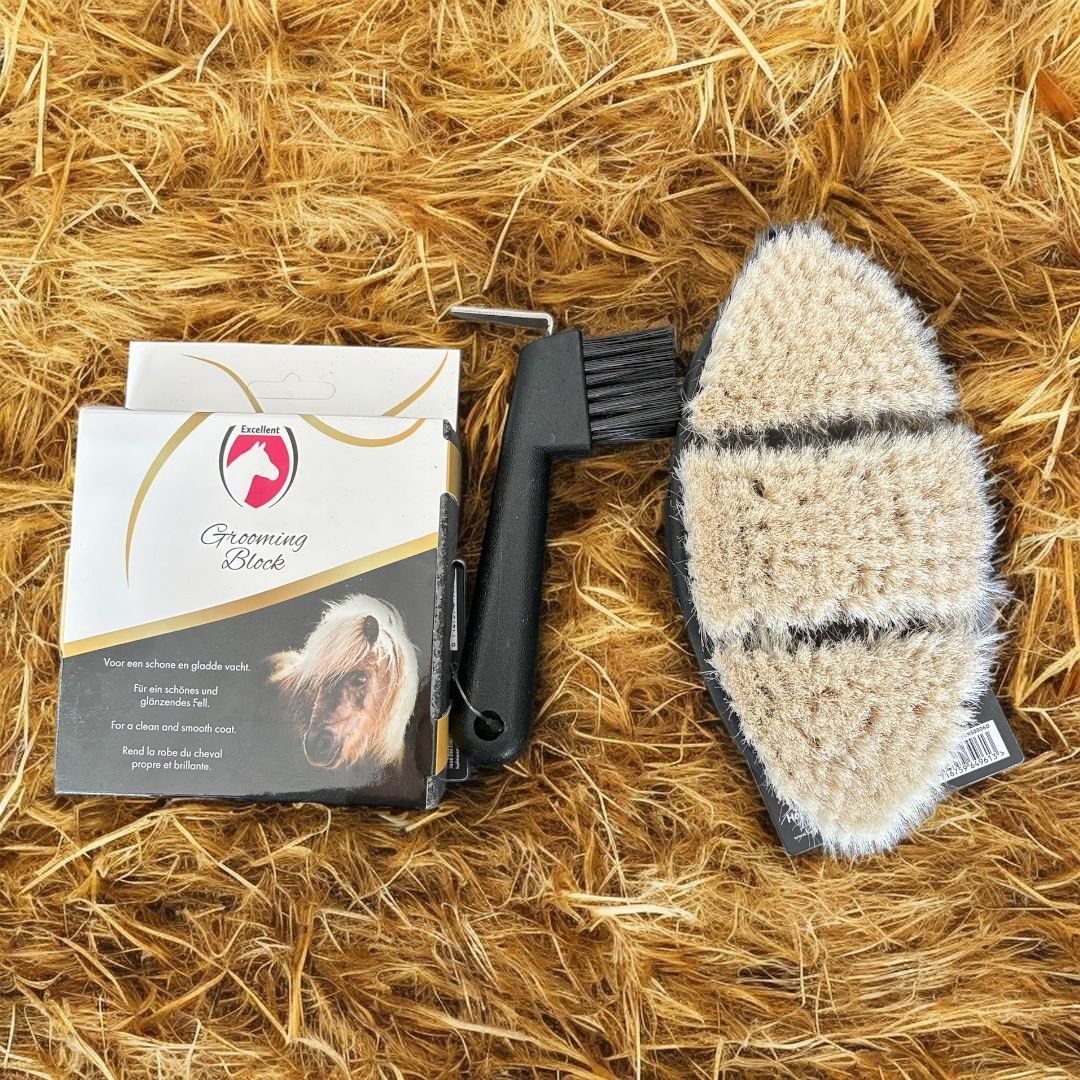 Een complete paardenverzorgingsset met een reinigingsborstel en een ovale roskam met zachte haren, op een bedje van hooi.