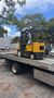 A yellow forklift is sitting on top of a tow truck.