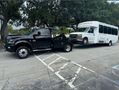 A tow truck is towing a bus in a parking lot.