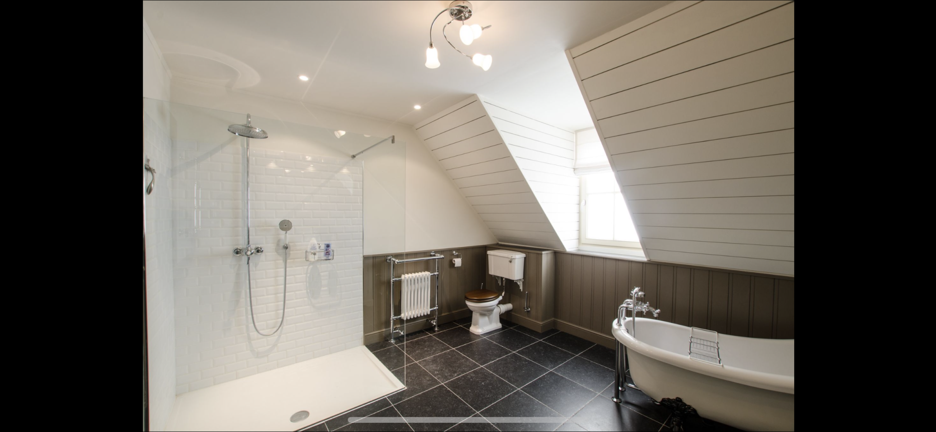 Een badkamer met bad, douche, toilet en raam.