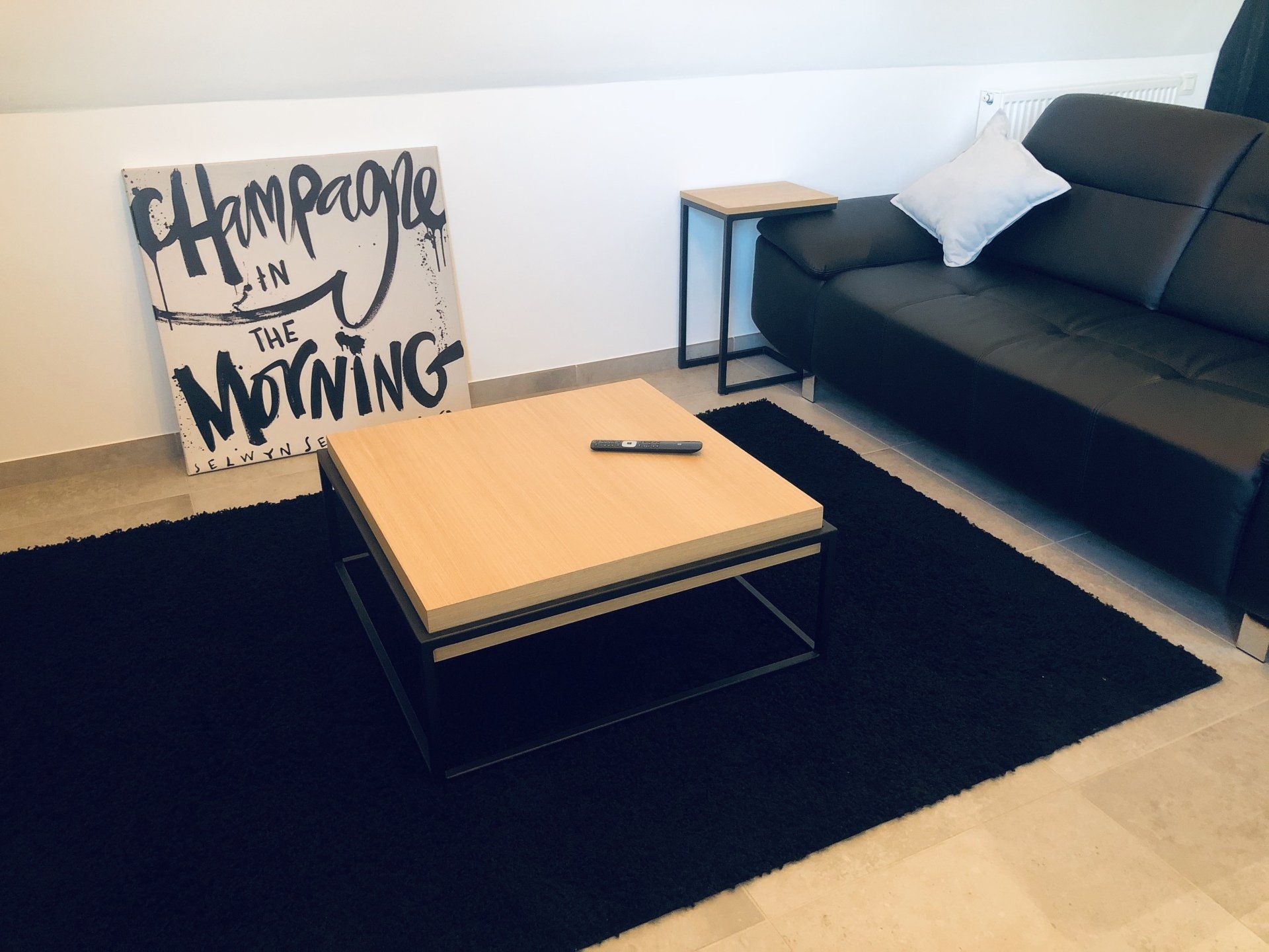 Een woonkamer met een bank, een salontafel en een bordje met de tekst 'champagne in the morning'