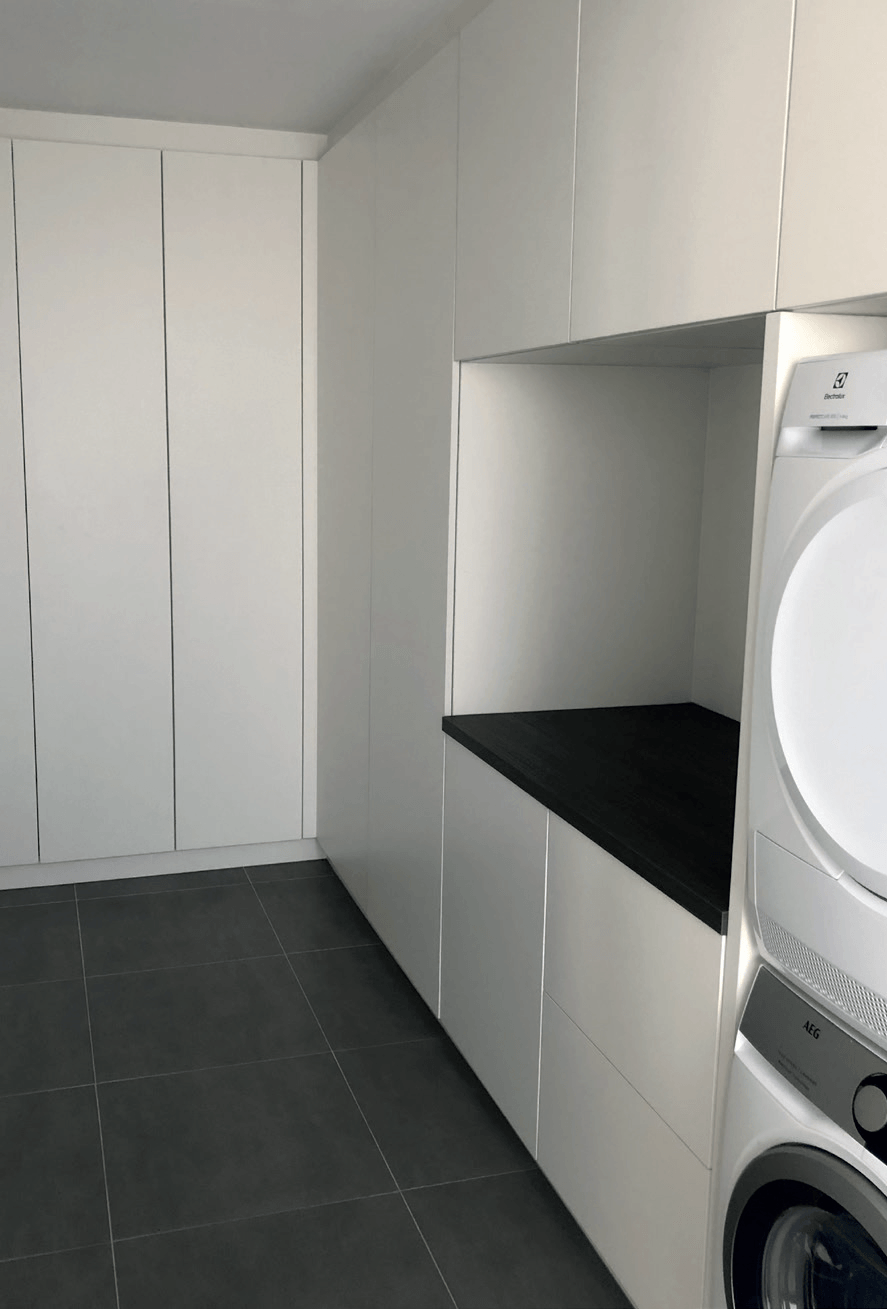 Een wasruimte met een wasmachine en droger bovenop elkaar.