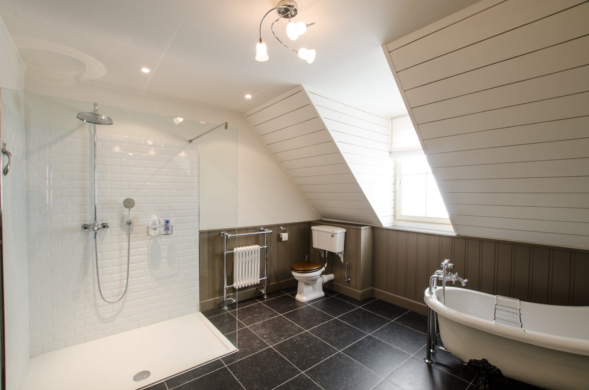 Een badkamer met bad, toilet, douche en raam.