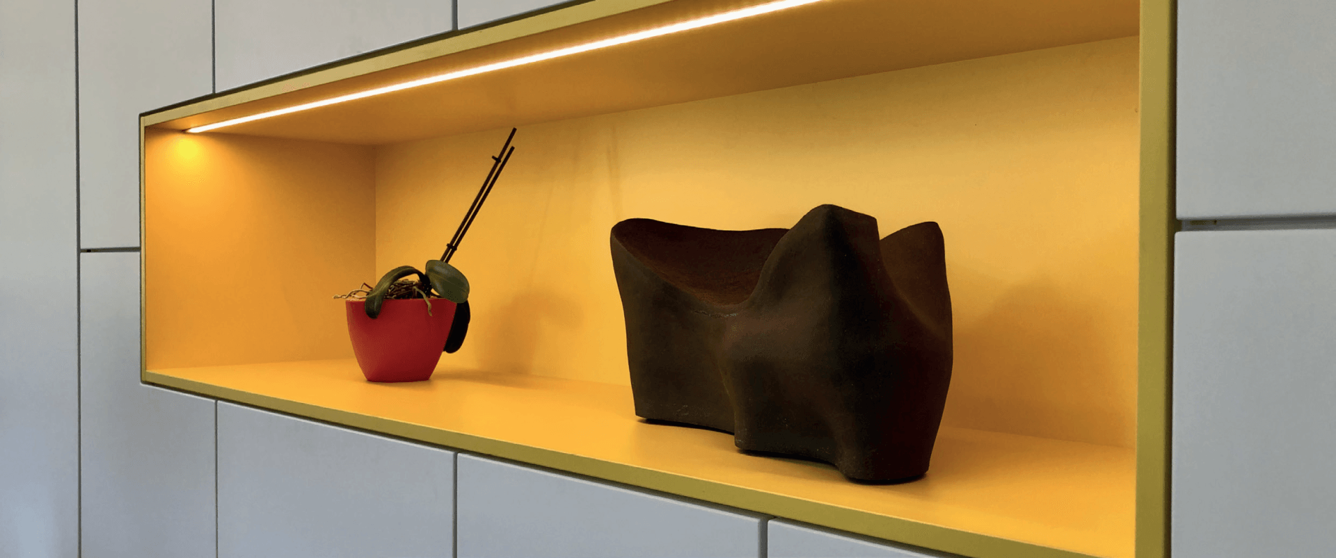 Een plank met daarop een vaas en een beeld.