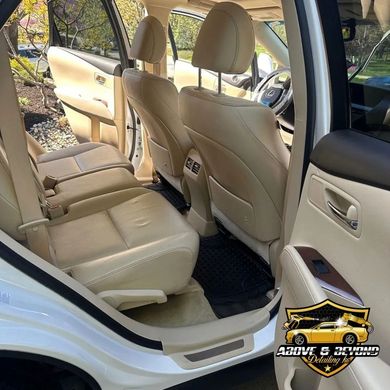 Beige leather interior of a white Lexus SUV; open back door.