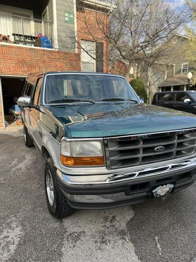 Green and silver Ford pickup truck parked near a garage.