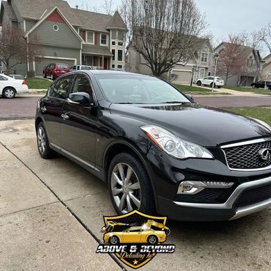 Black Infiniti SUV parked on a driveway in front of a suburban home; logo for Above & Beyond Detailing at the bottom.