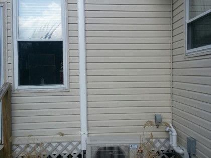 Exterior of a building with vinyl siding, windows, and a downspout.