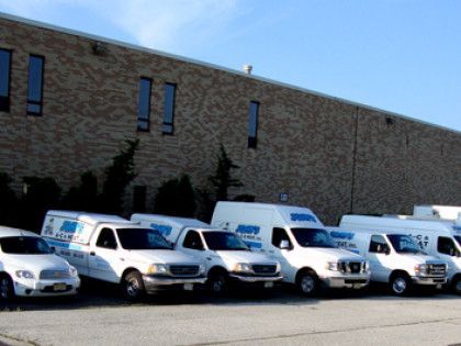 White service vehicles parked in front of a brick building under a blue sky.