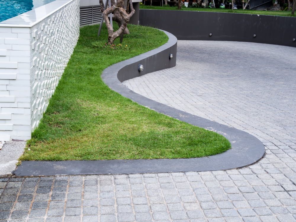 A Curved Driveway Leading To A Swimming Pool — Tuncote Concrete Constructions in Medowie, NSW
