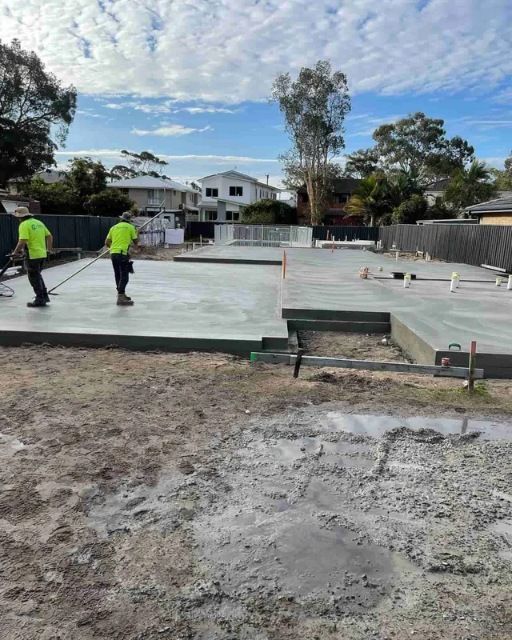 Two Men Are Working On A Concrete Floor In A Dirt Field — Tuncote Concrete Constructions in Raymond Terrace, NSW