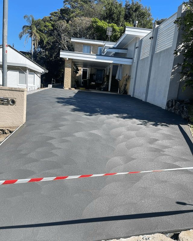 A Driveway Leading To A House With A Red And White Tape — Tuncote Concrete Constructions in Anna Bay, NSW