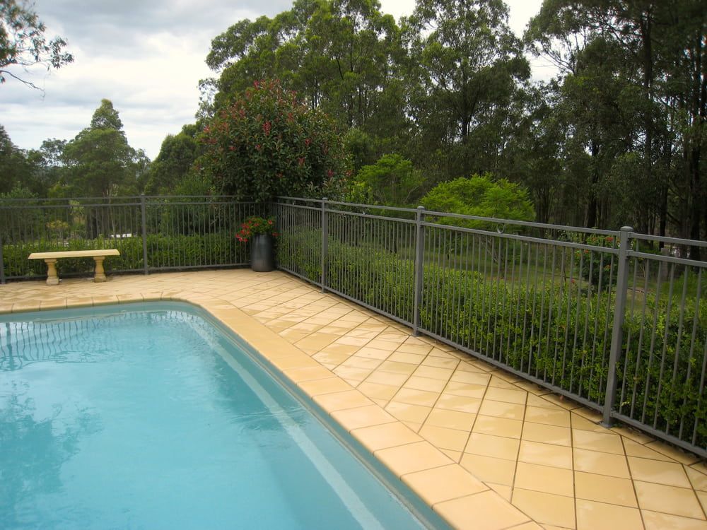 A Swimming Pool With A Fence Around It And Trees In The Background — Tuncote Concrete Constructions in Anna Bay, NSW