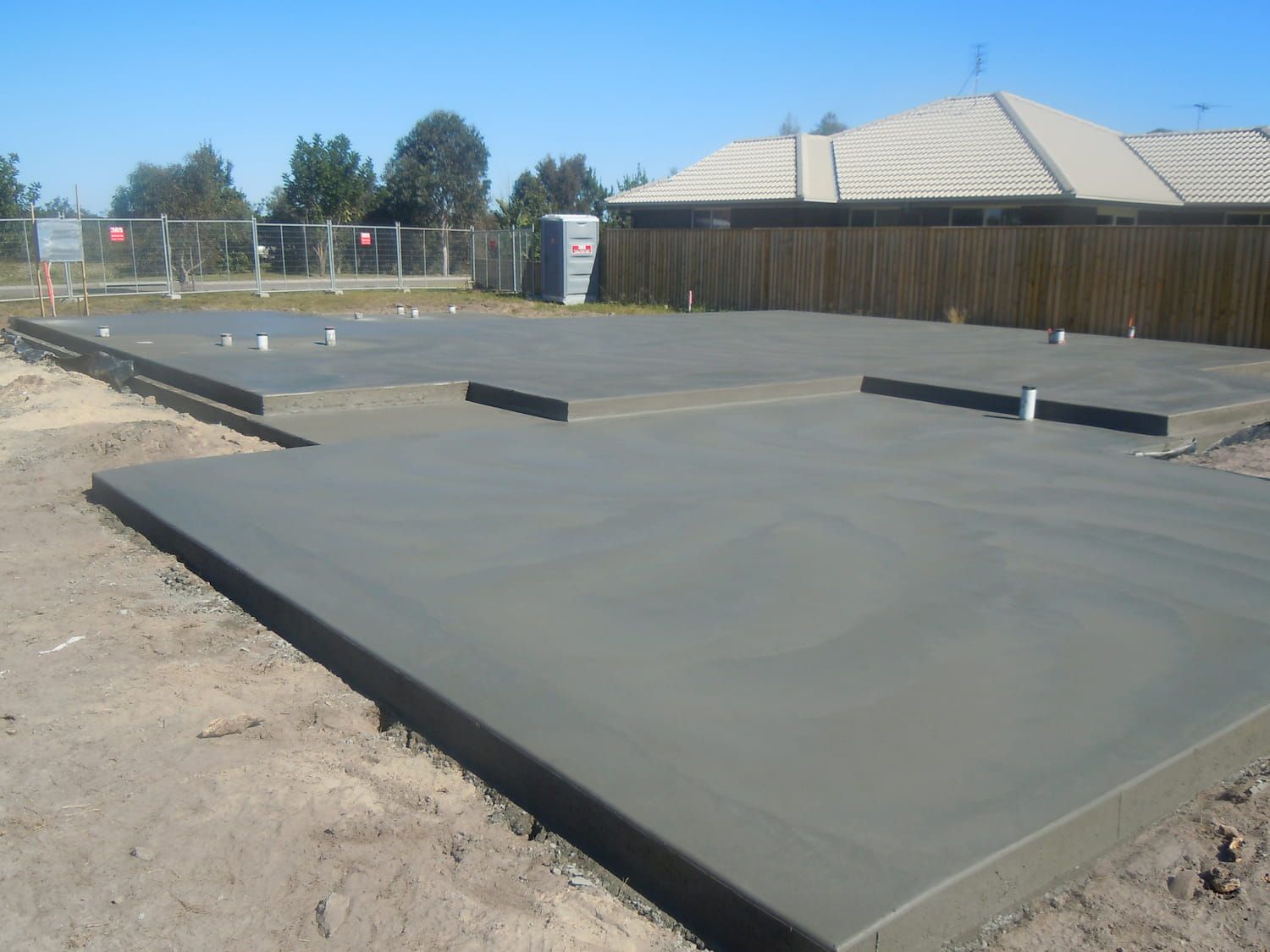 A Concrete Floor With A House In The Background — Tuncote Concrete Constructions in Anna Bay, NSW
