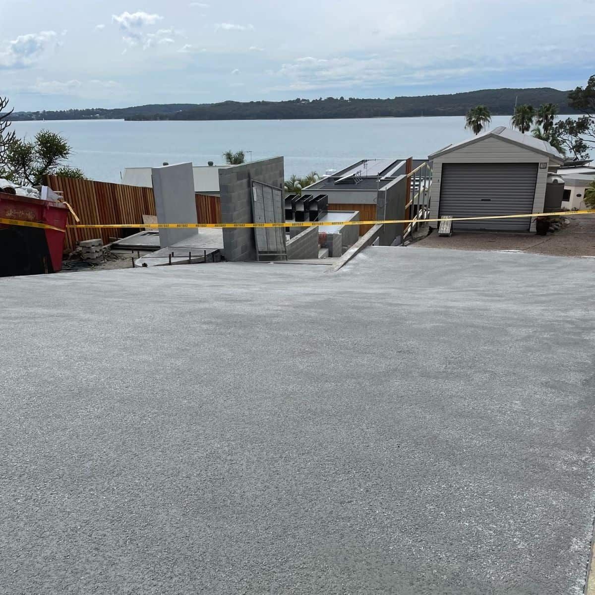 A Concrete Driveway Leading To A House With A Garage Next To A Body Of Water — Tuncote Concrete Constructions in Nelson Bay, NSW