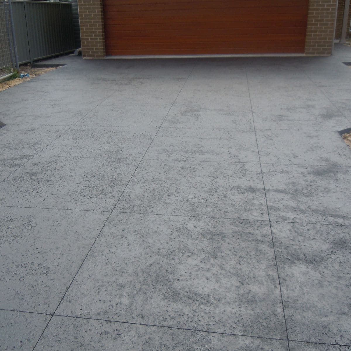 A Concrete Driveway With A Garage Door In The Background — Tuncote Concrete Constructions in Medowie, NSW
