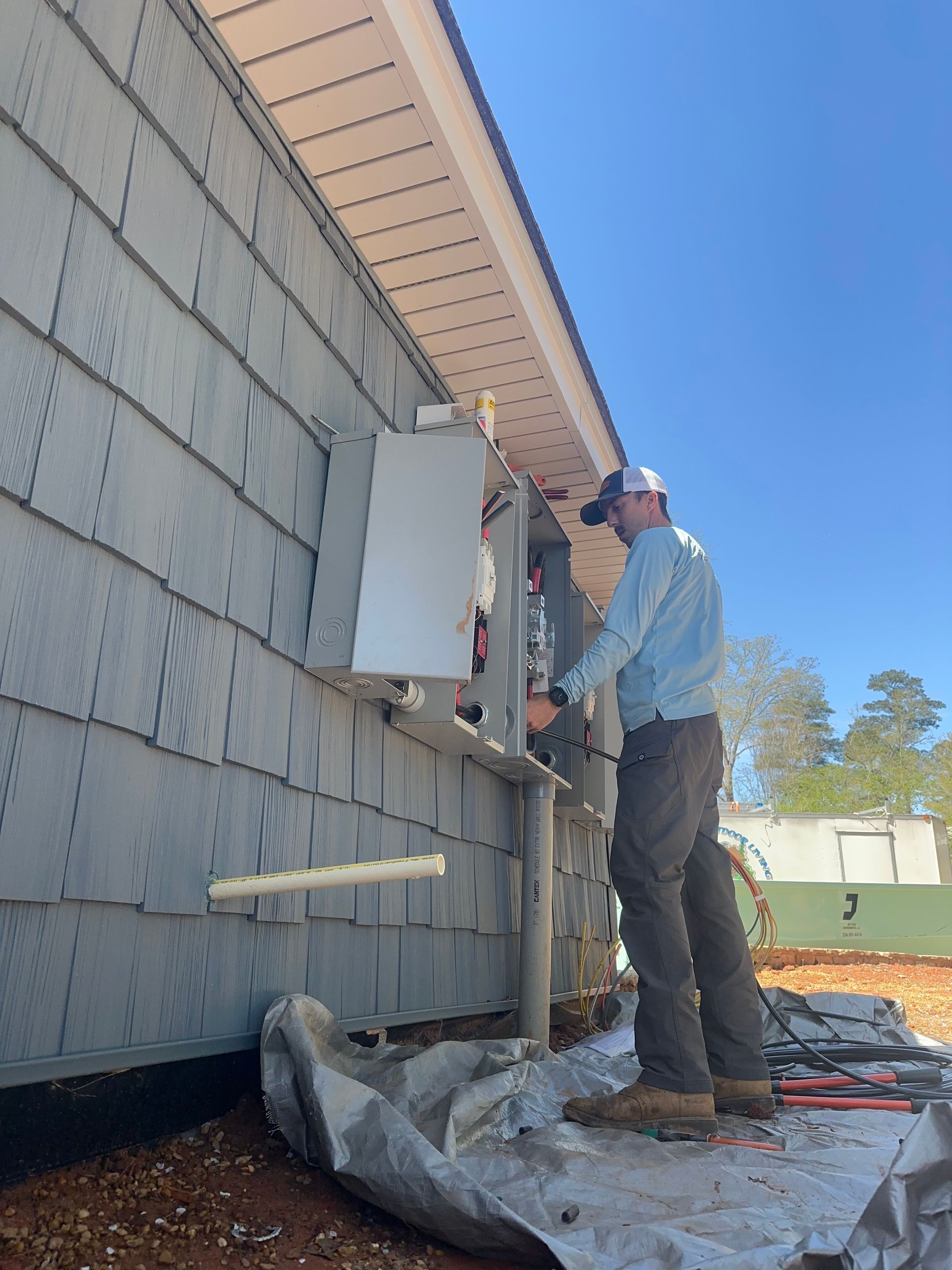 A man is working on an electrical box on the side of a building.