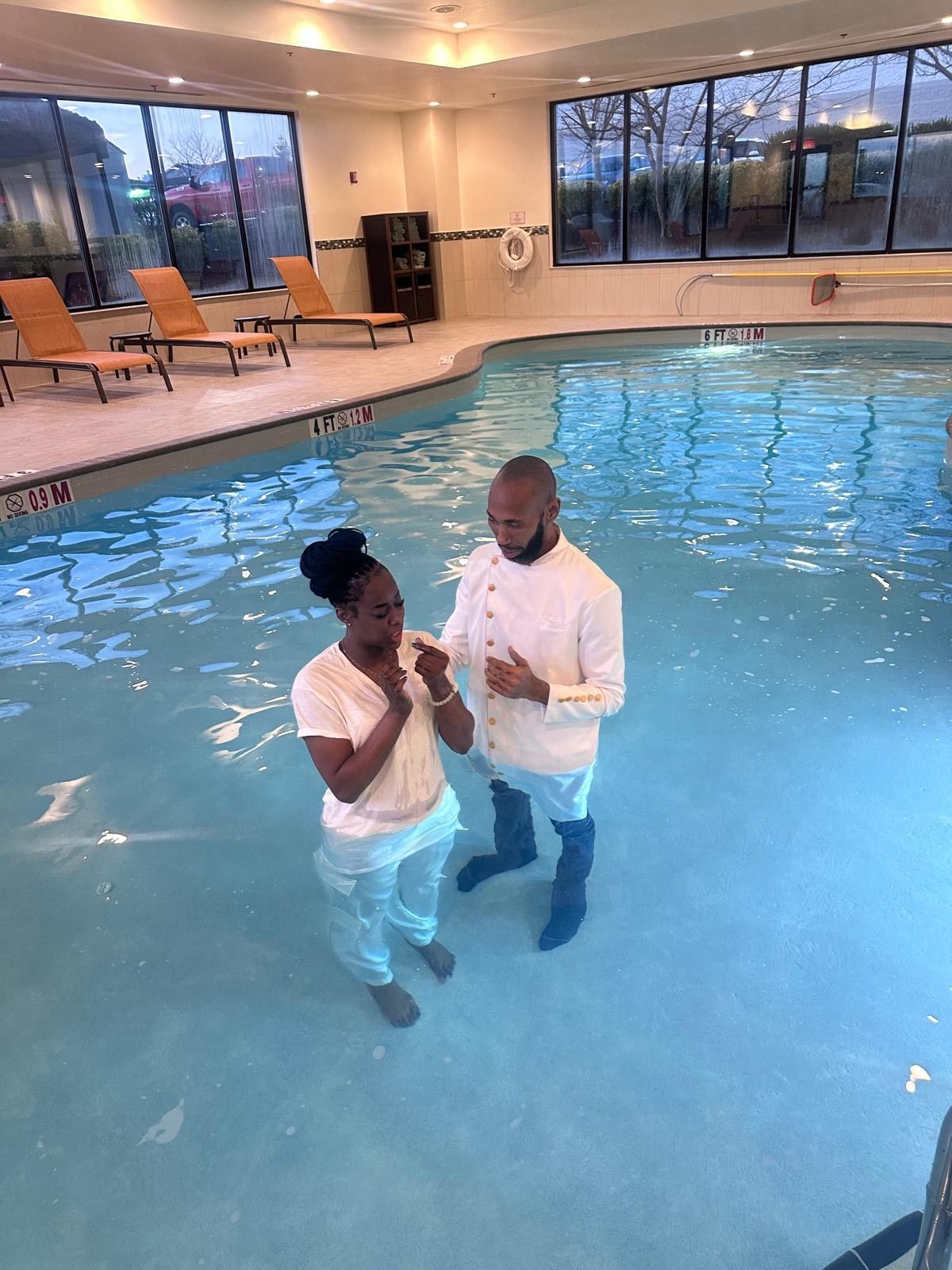 A man and a woman are standing in a swimming pool.