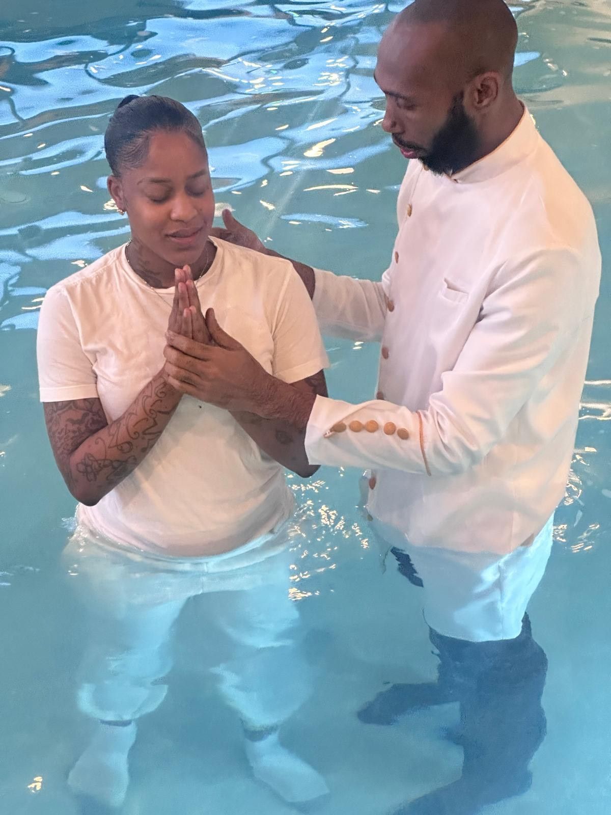 A man is baptizing a woman in a pool.