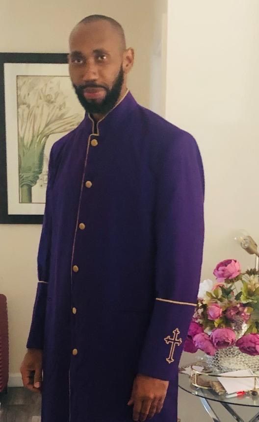 A man in a purple coat with a cross on the sleeves