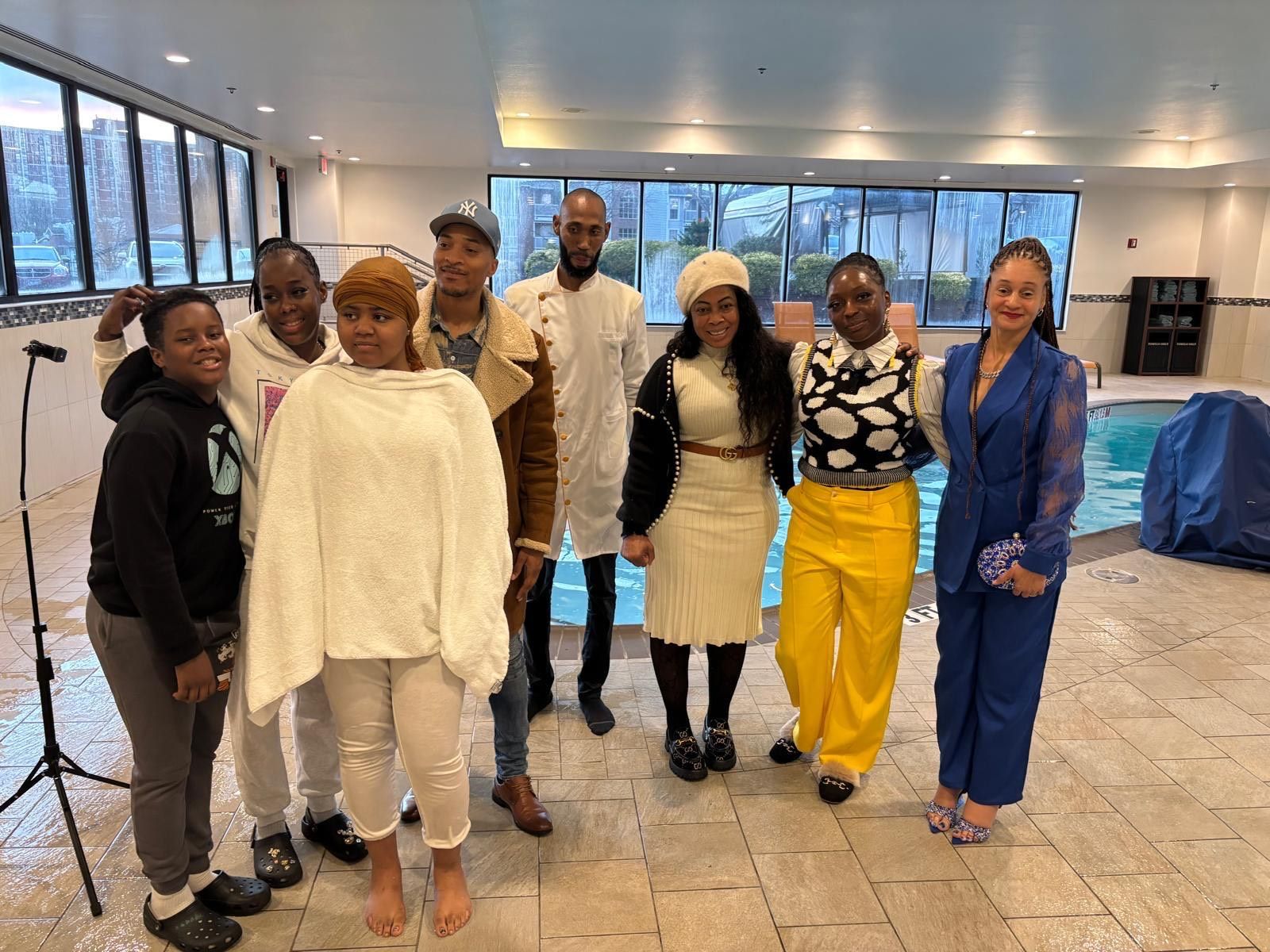 A group of people are posing for a picture in front of a swimming pool.