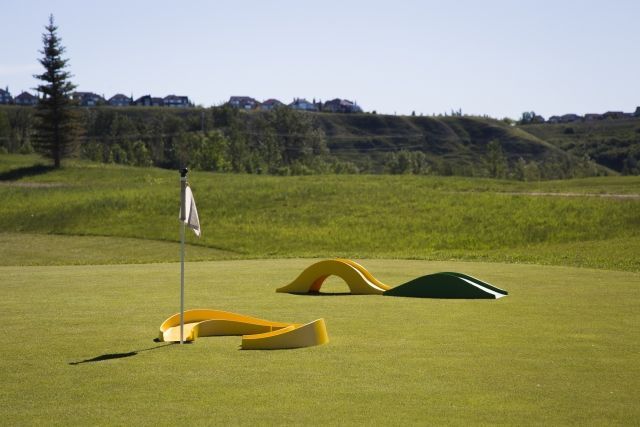 A putting green with yellow and green obstacles; a flag marks the hole.