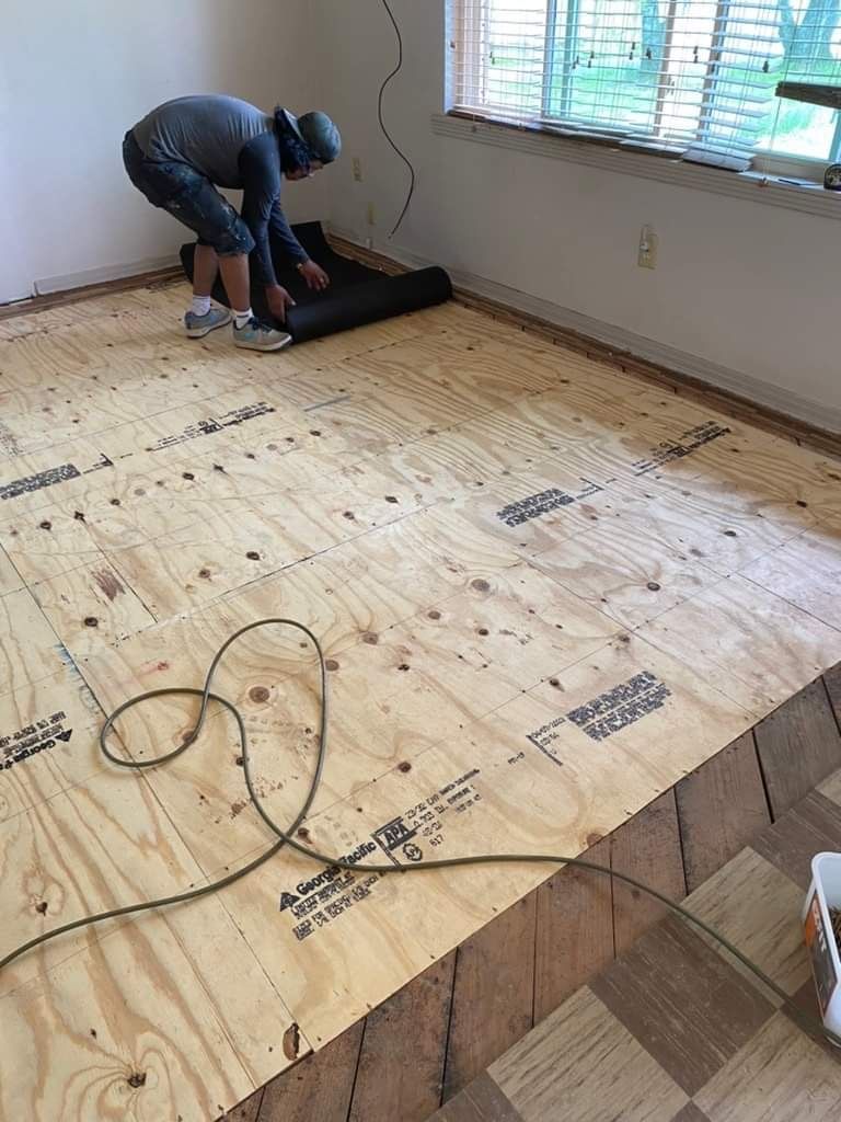 A man is working on a wooden floor in a room.