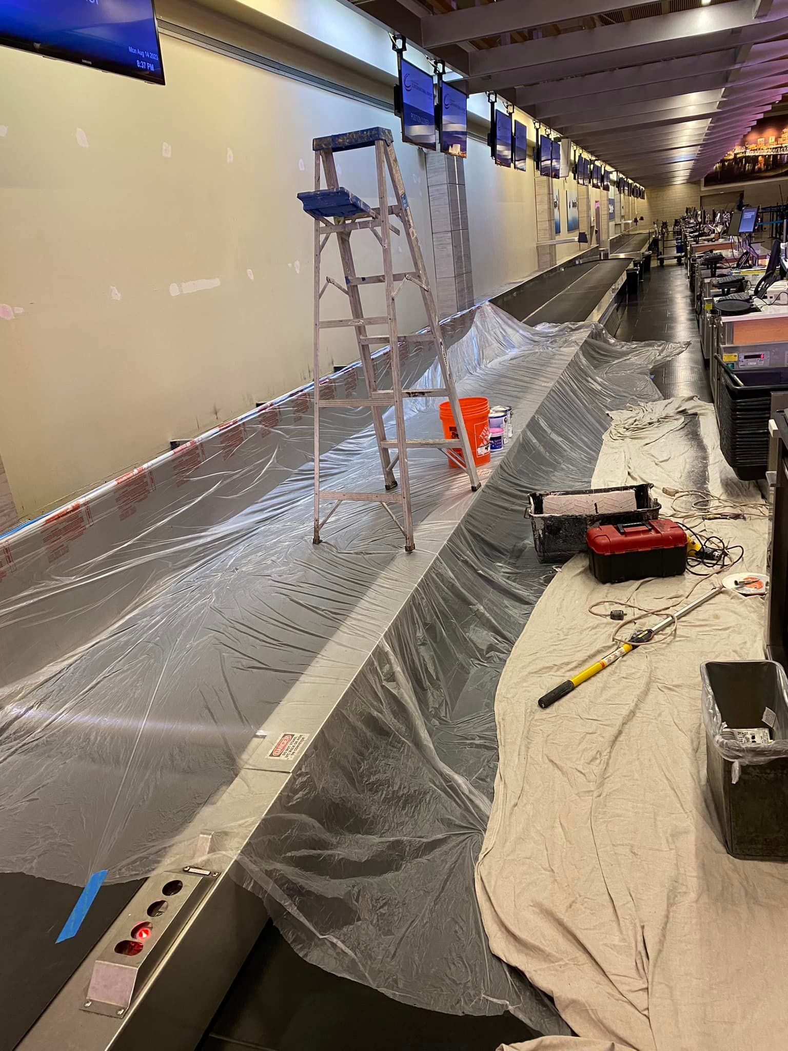 A ladder is sitting on top of a conveyor belt covered in plastic.
