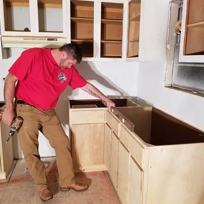 A man in a red shirt is working on a kitchen