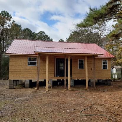 A small wooden house with a red roof is being built in the woods.