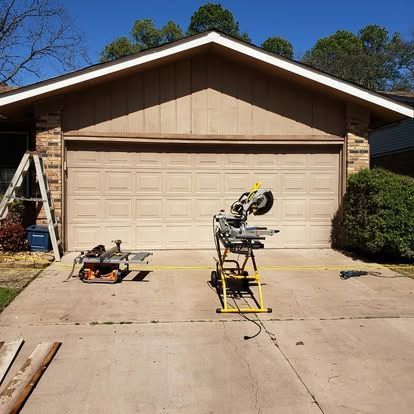 A garage door is being repaired and a saw is sitting in front of it.