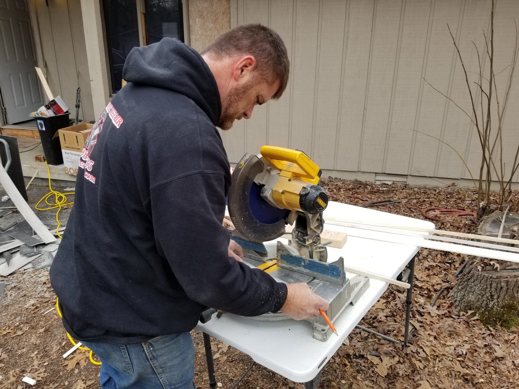 A man is cutting a piece of wood with a miter saw.