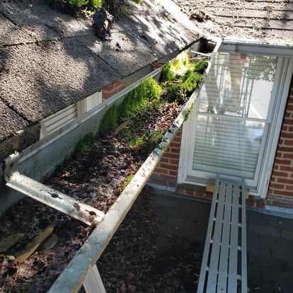A gutter is sitting on the side of a house next to a window.