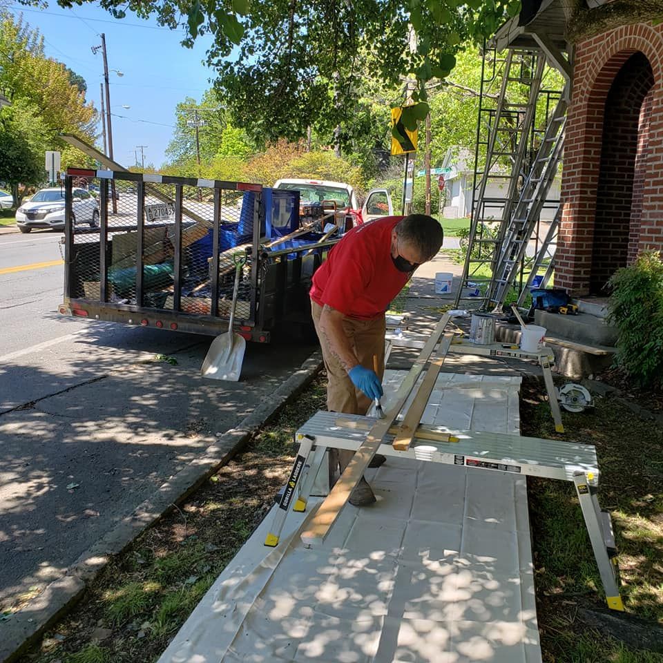 A man in a red shirt is painting a door on a sidewalk.