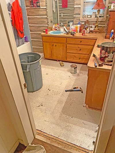 A bathroom with a sink , cabinets , and a trash can.