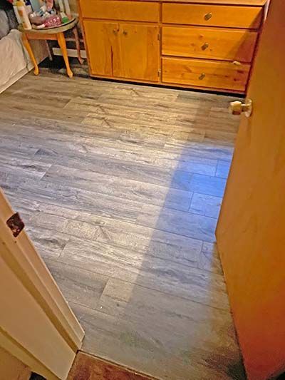 A bedroom with a wooden floor and a dresser.