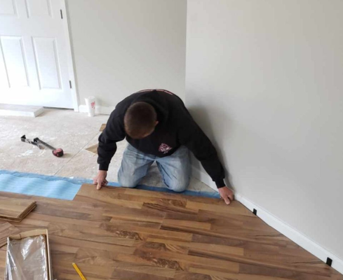An empty room with a wooden floor and a picture frame on the wall.