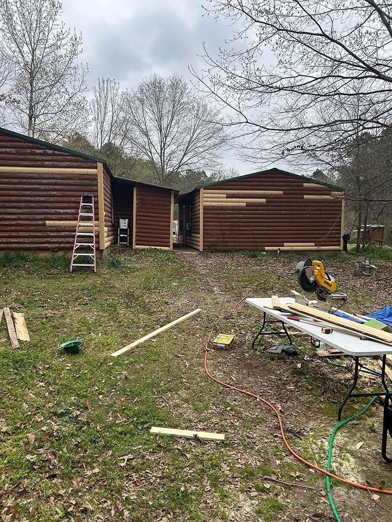 A group of log cabins are being built in a grassy area.