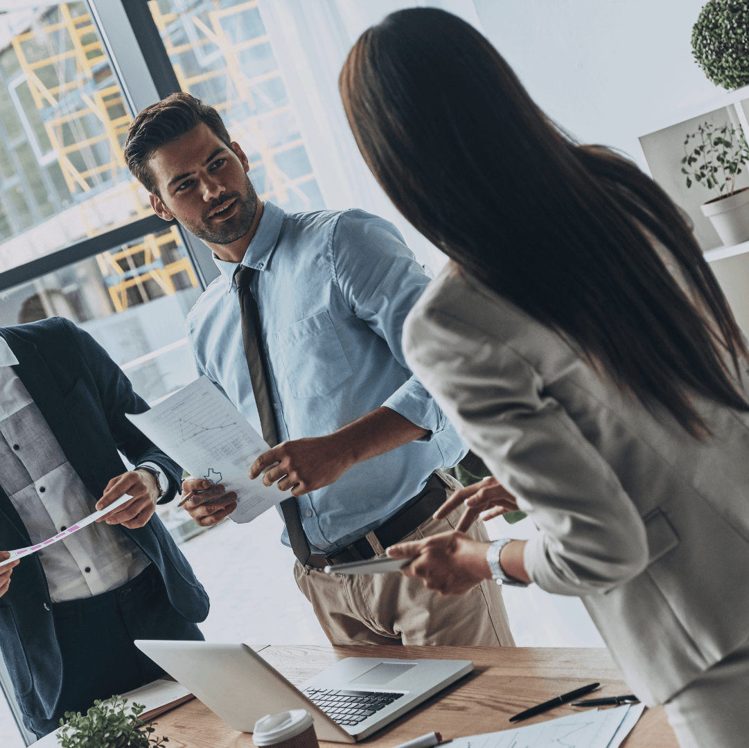 A group of people standing around a table with laptops and papers