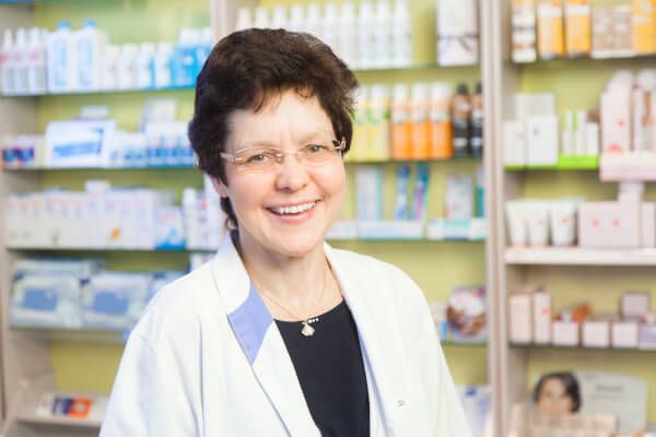 Eine Apothekerin lächelt in einer Apotheke.