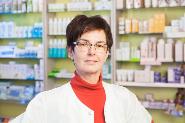 Eine Apothekerin steht vor einer Apotheke.