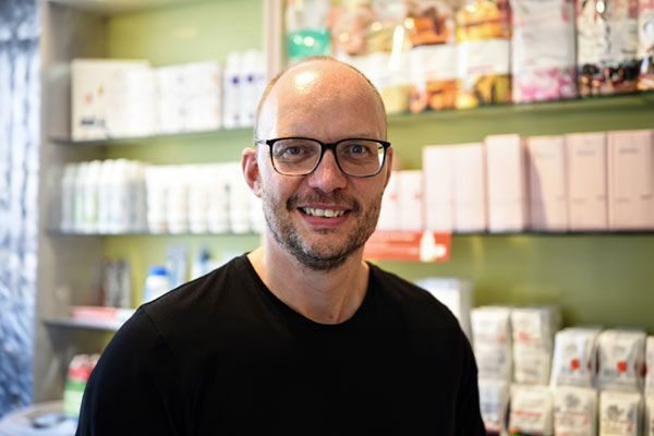 Ein Mann mit Brille steht in einem Geschäft vor einem Regal.